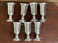 Seven cups arranged on wooden surface, front view