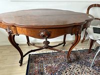 Front view of scalloped oval walnut veneer top, apron carving, legs and stretcher