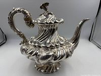 Front-side view of teapot showing overall shell-form body, spout, handle and lid