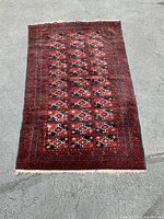 Full view of the hand woven area rug laid flat on a concrete surface, showing the overall geometric pattern and colors.