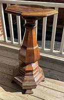 Front view of the wooden pedestal stand showing hexagonal top and faceted column