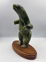 Front view of carved green stone dancing bear sculpture on wooden base