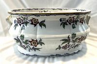 Front-quarter view of the oval foot bath showing full exterior shape, floral decoration, and handles