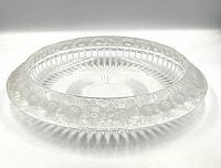 Round clear crystal bowl on white background showing floral border and interior fluting