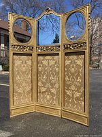 Frontal view of the three-panel gilded screen showing central mirror, oval side mirrors and silk textile panels