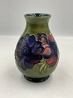 Front and side views of Moorcroft pottery vase with deep crimson and violet poppies on olive green background.