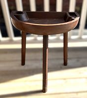 Angled front view of the primitive antique Shaker style pine games table showing the semi-circular top and three legs.