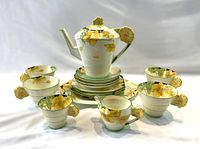 Front view of entire tea set arranged on white background showing teapot, cups, saucers, plates, creamer, sugar bowl, platter