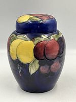 Jar with lid on, front view showing multicolor fruit motif on cobalt background