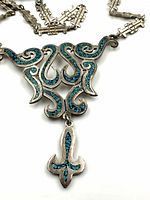 Close-up of triangular pendant showing inlaid turquoise mosaic detail