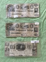 Front sides of all three notes laid flat on green cloth