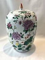 Front view of the large oval-shaped porcelain ginger jar showing pink and purple flowers with green leaves on white background and reddish-orange lid finial.