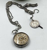 Watch, chain, and key arranged on flat surface