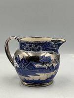 Side view photo showing floral and foliage silver detailing on cobalt blue creamer