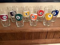 Eight clear glass tumblers arranged in a row, each with different billiard ball graphics showing numbers 15, 12, 6, 9, 13, 3, 1, 2.