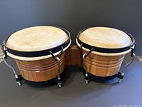 Side view of the vintage bongo drums showing natural wood grain shells and mounting hardware.