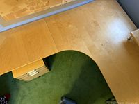 Top view of light birch wood corner desk showing surface area and filing cabinet below.