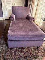 Front view of the chaise lounge showing cushioned seat and back with rolled arm on one side in dusty purple/mauve chenille fabric