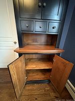 Lower cabinet doors open showing interior shelf and cable management hole in top surface