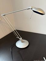 Full view of the matt silver desk lamp showing its adjustable double arms, weighted base, and round adjustable head.