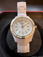 Front view of white Fossil ladies watch showing mother-of-pearl face, silver markers, hands and trim, white plastic link band.