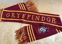 Gryffindor word and crest visible on knitted scarf with air-dried fringes.