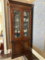 Full front view showing upper leaded glass doors with interior shelves and lower wood doors