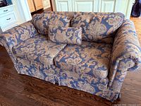 Full view of the custom loveseat showing floral paisley pattern upholstery, two seat cushions, two large back cushions, and extra small cushion