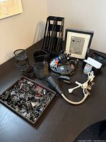 All items arranged on a black table showing 3-tier file holder, rotating desk organizer, binder clips, lamp, frame, and other supplies