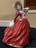 Front angled photo showing full red dress, bonnet and left hand holding white gloves.