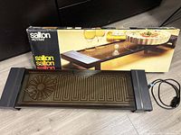 Salton Hotray warming tray displayed with original packaging box, showing front and side views of the tray and power cord.