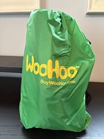 Green packed WooHoo inflatable lounger in storage bag with yellow logo