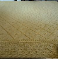Overview of the buttercream yellow wool rug showing the main diamond pattern and border