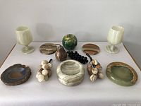 Full lot showing variety of agate and onyx carved items including goblets, bowls, faux fruits, and coasters arranged on white surface.