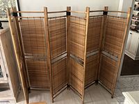 Full view of three bamboo double panel folding dividers standing together in an indoor setting