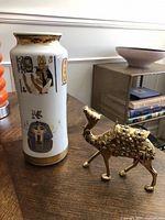 Image showing the Limoges vase and brass camel figurine on a wooden surface with a side table and books in the background.