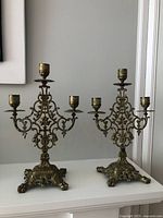 Full view showing both matching vintage brass filigree 3-arm candelabras.