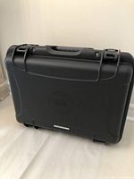 Closed black hard case showing front with handle, latches and rounded edges.