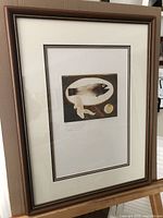 Framed limited edition print shown from front, displaying the full piece within a brown wood frame with double matting.