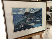 Framed blue tone coastal village print by Marc-Aurele Fortin shown angled from front