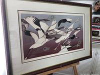 Framed artwork showing flying geese in flight with details of colors and composition.