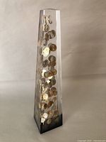 Straight-on front view of the clear lucite obelisk embedding several 1970s pennies visible inside