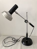 Full view of MCM cantilever desk lamp with black base and metallic head