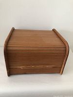 Front view of teak tambour roll top storage box showing closed tambour door and rounded edges.