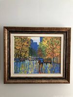 Full view of the framed street scene painting showing the frame and overall composition.