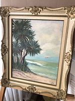 Full view of the framed coastal landscape painting featuring palm trees and ocean waves with a seagull in flight.
