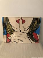 Front view of the Pop Art print sealed in original packaging showing a woman with finger on lips in a 'shush' gesture.