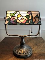 Front view of lamp turned on showing stained glass shade and bronze base