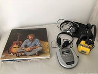 Wide view showing vinyl albums, multiple headphones, and portable CD player on table