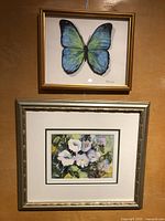 Two framed watercolours: butterfly and floral paintings shown hanging on a wall.